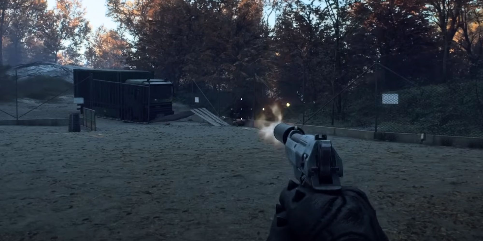 A first-person POV of hands wearing black gloves holding and firing a suppressed pistol in a wooded area during Autumn.