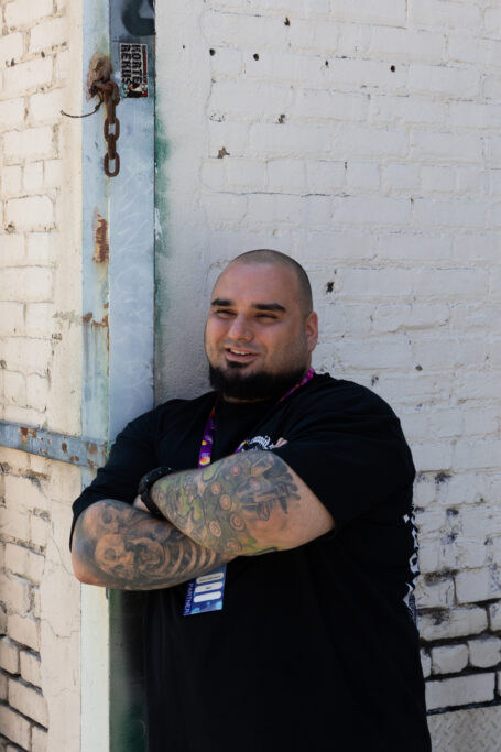 Man standing against a wall, smiling with arms folded