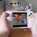 Hands holding Anbernic RG Cube with Crash Team Racing gameplay on screen