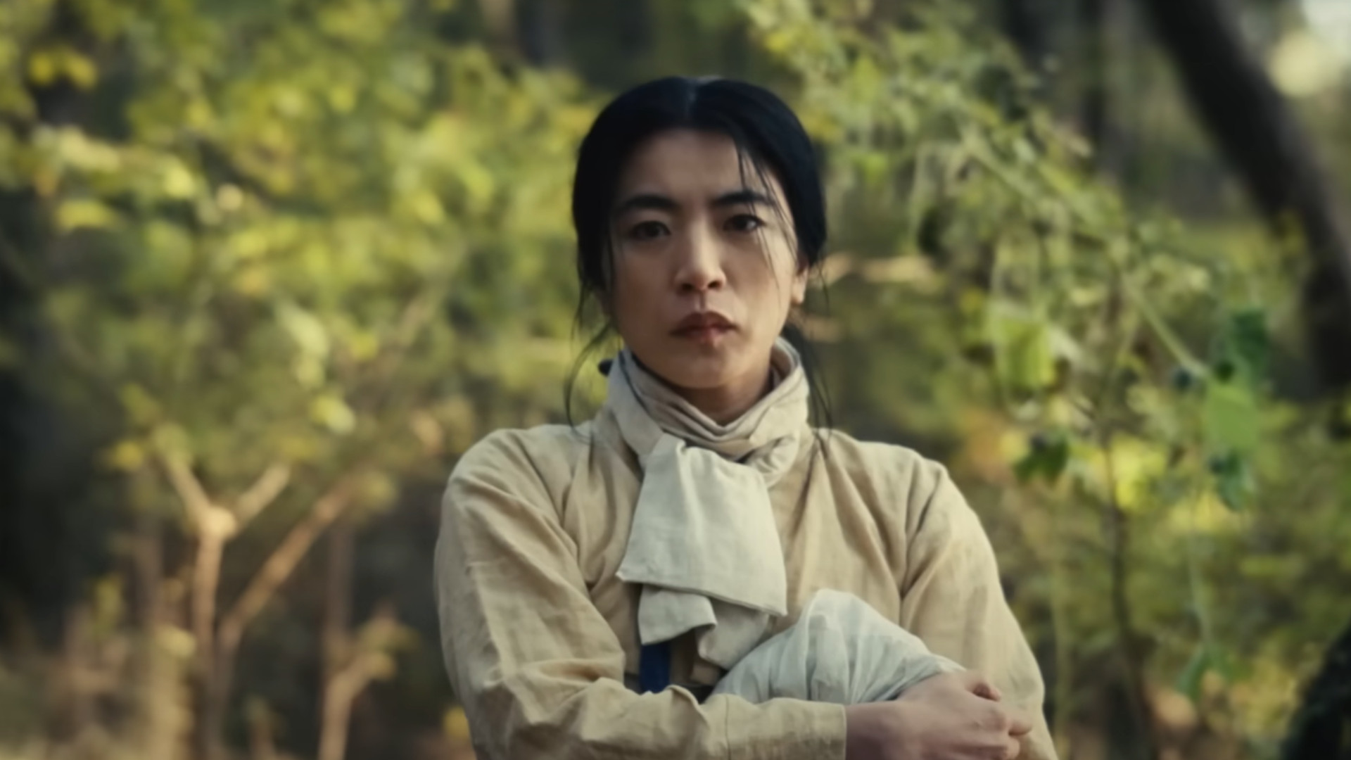 A woman looking concerned in the woods during the Apple TV Plus show, Pachinko.