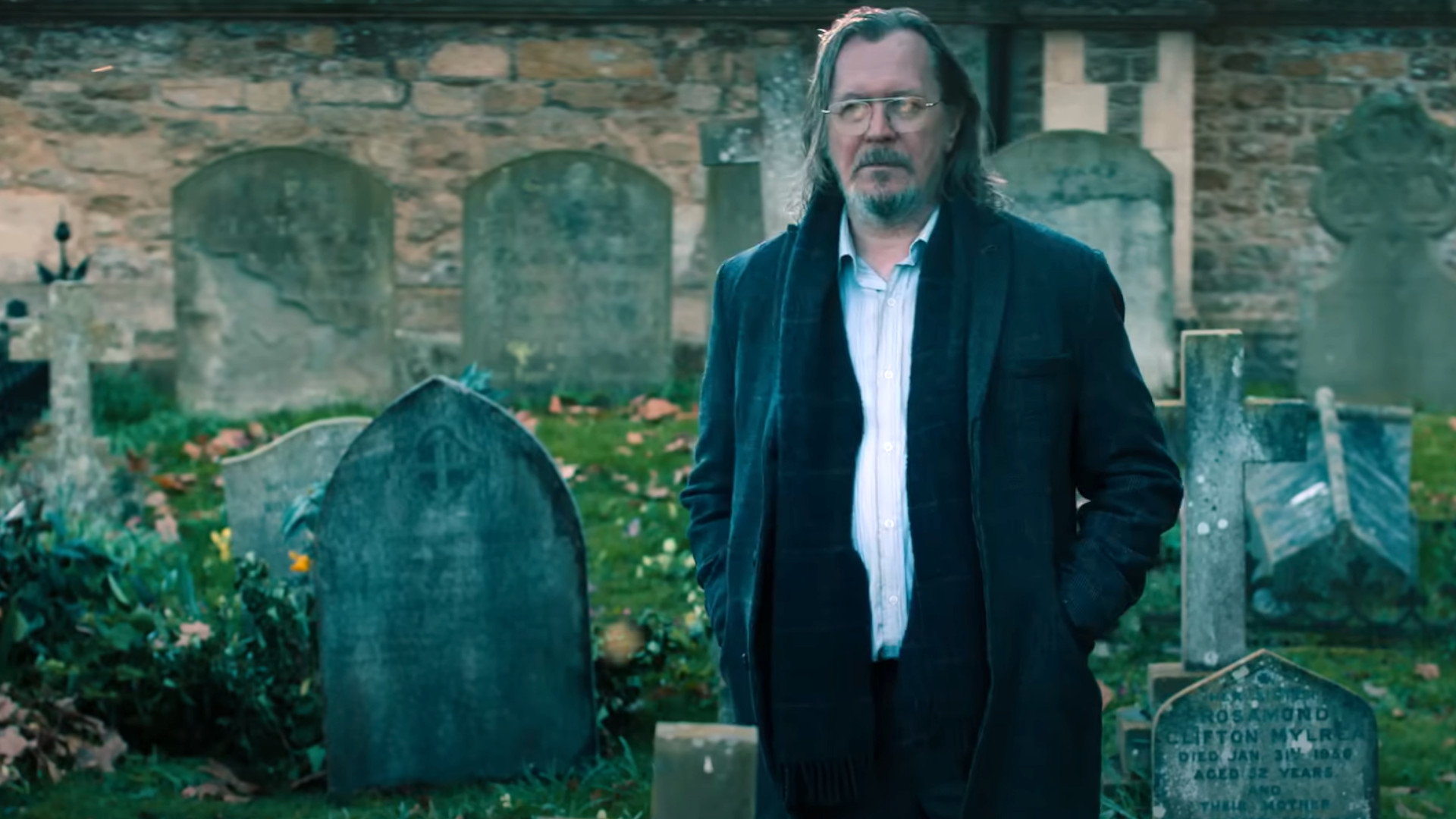 Gary Oldman as Jackson Lamb standing in a graveyard during the Apple TV Plus show, Slow Horses.