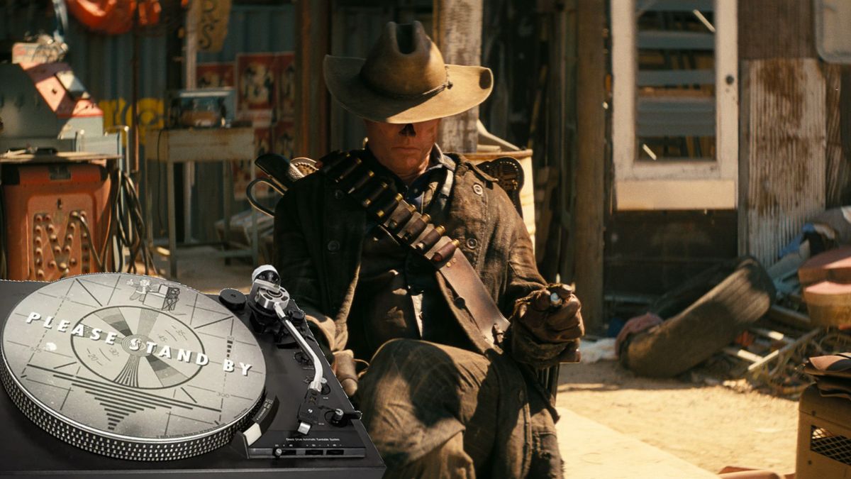 The Ghoul sitting in a wasteland town with a 'please stand by' record player in the foreground