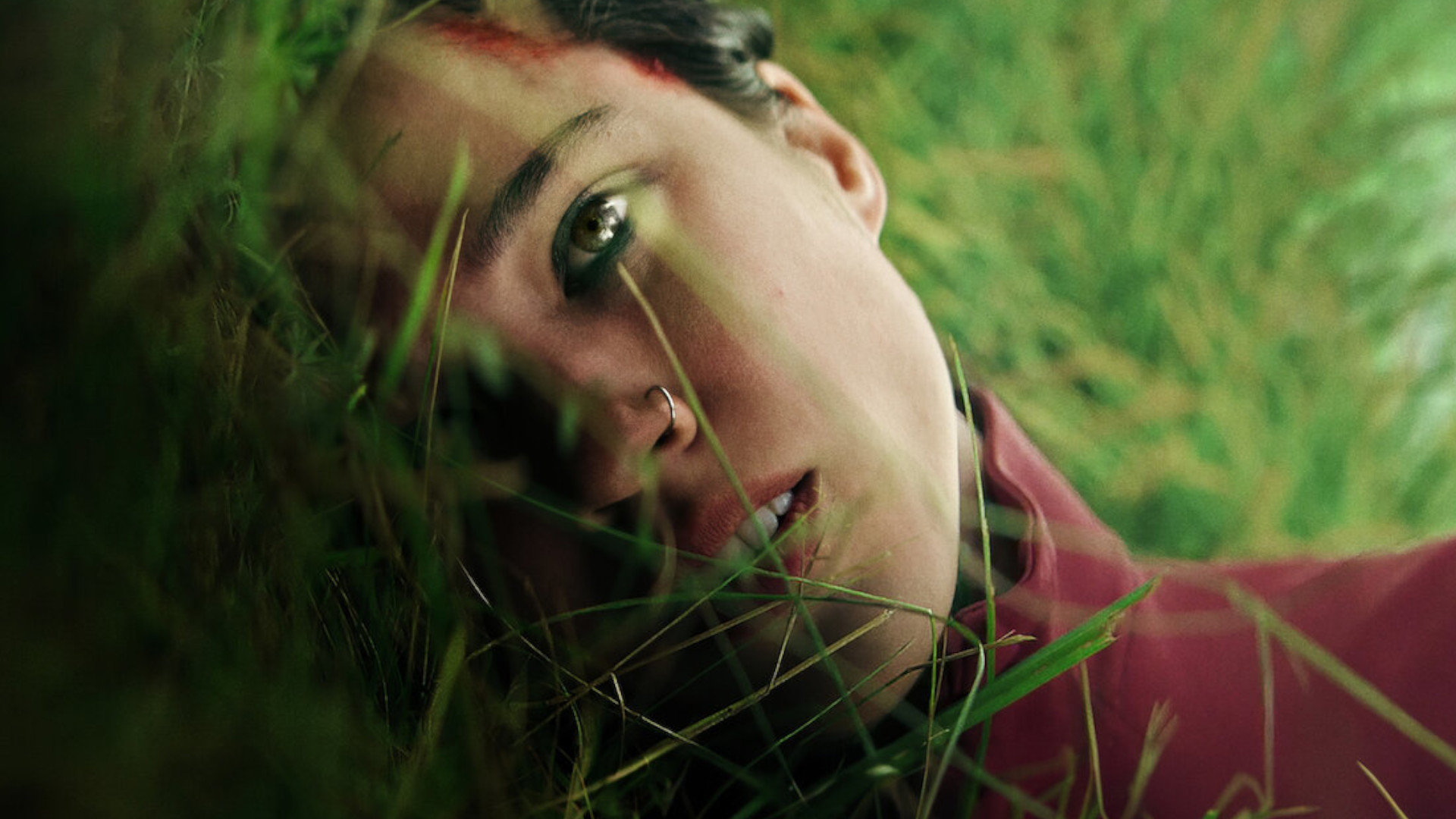 Kelsey Asbille lying on some grass during the upcoming horror movie, Don't Move.