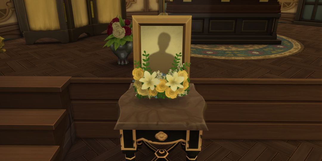 A memorial photograph frame, surrounded by flowers, stands on a table.