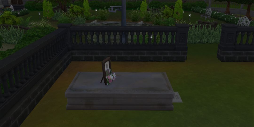 A grave site in the Sims 4. It is a flat stone slab with a photo on top.