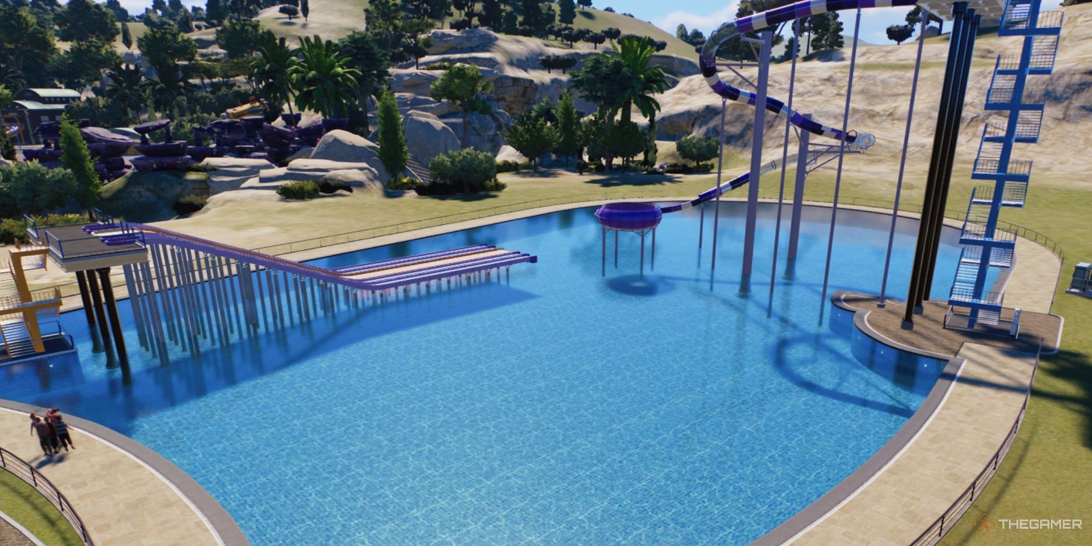 A flume and a body slide are build in a pool in Planet Coaster 2.