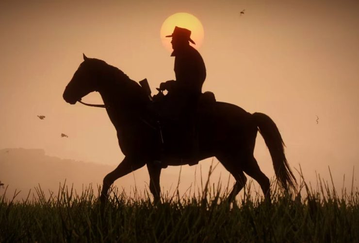 Red Dead Redemption 2 screenshot showing the silhouette of a man with a cowboy hat on horseback, a glowing sun seen behind him