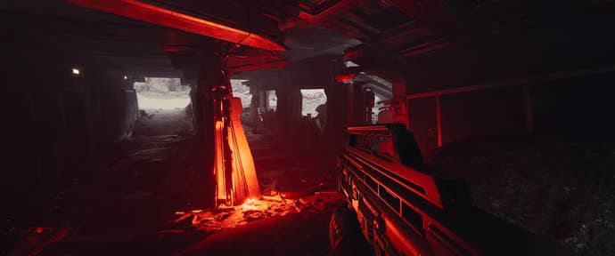 Red lighting illuminates the interior of a wrecked spaceship in EVE: Vanguard. A players holds an assualt rifle, FPS view.