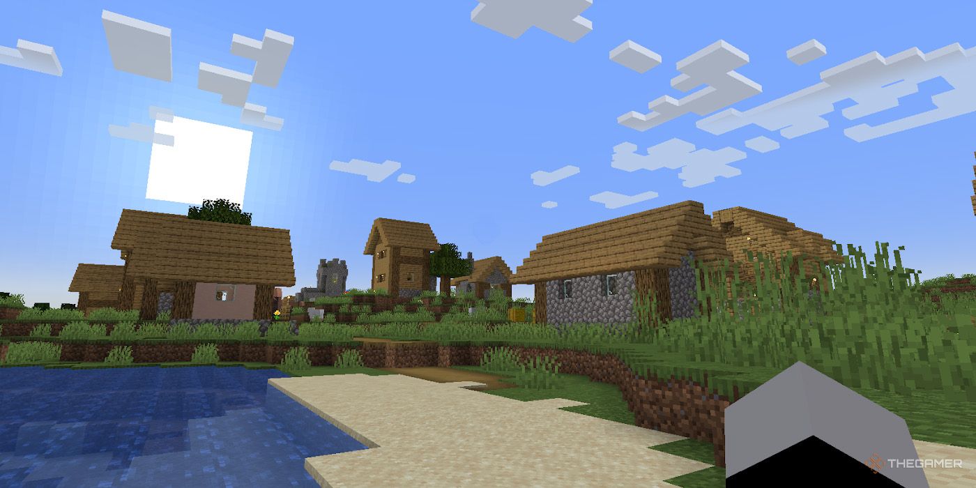 A village in a plains biome borders a thin beach in Minecraft.