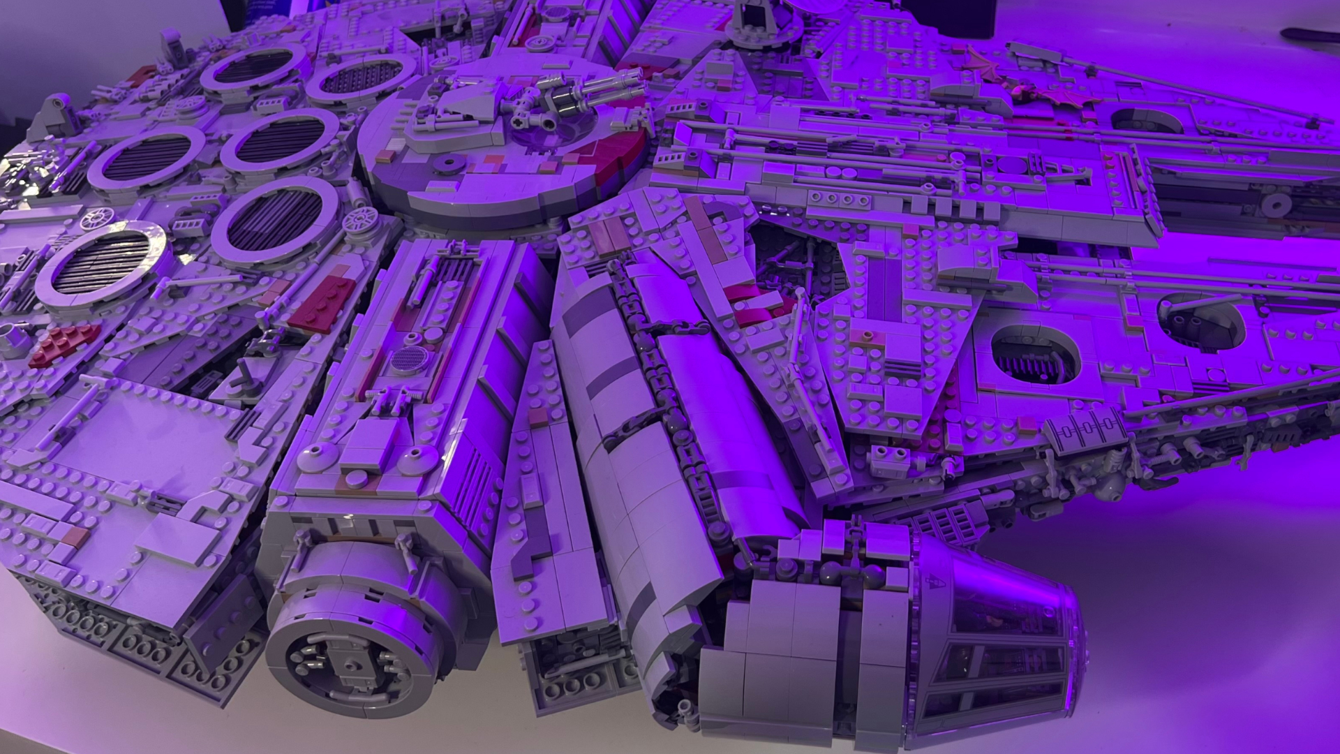 A side-on view of the Lego UCS Millennium Falcon, bathed in a purple light