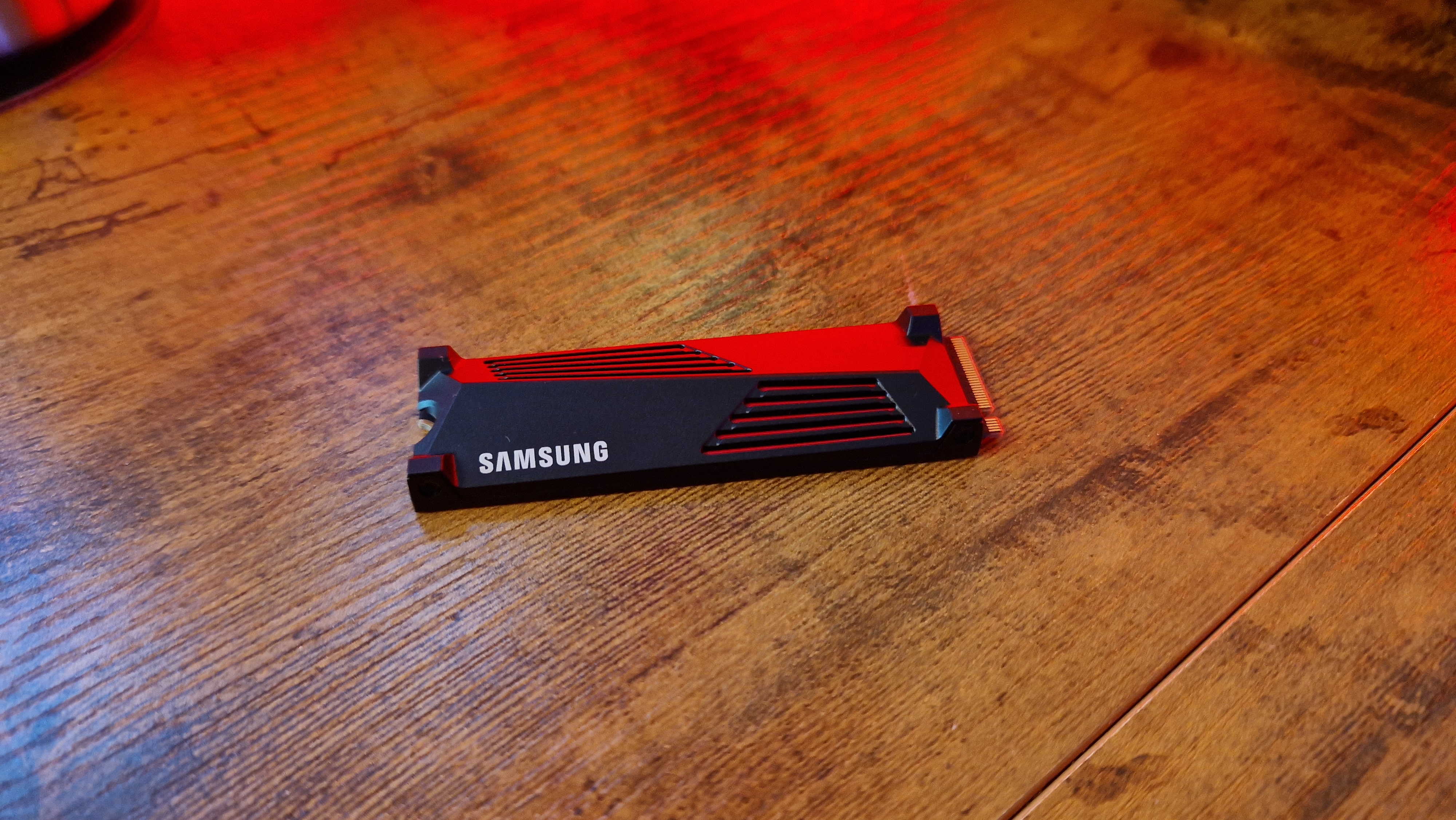 Samsung 990 Pro 4TB with a heatsink on a walnut desk with red lighting