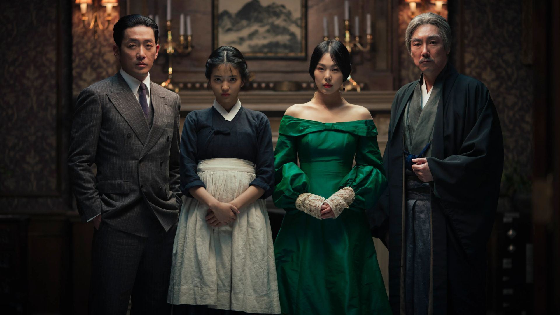 The cast of The Handmaiden standing together in a dark room.