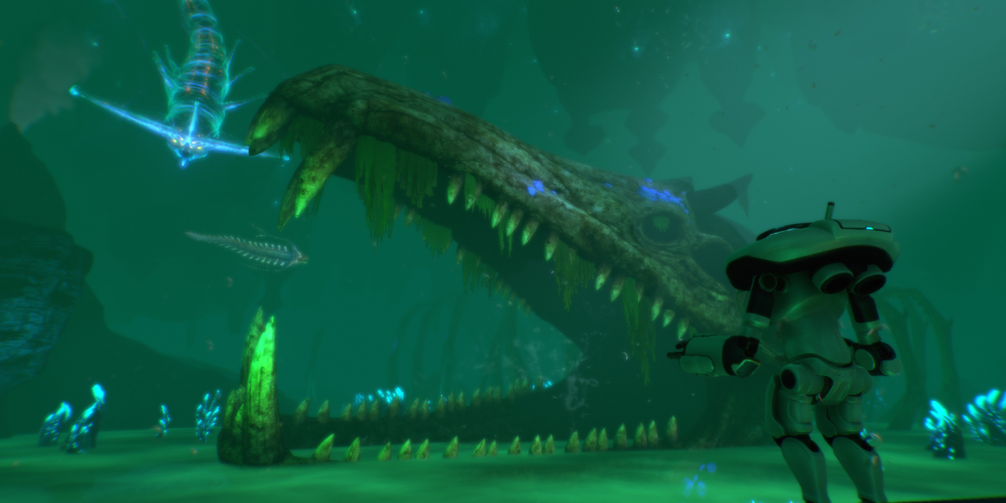 A diver in a mechanical suit observes a giant skeletal remains of a massive creature underwater, with bioluminescent fish swimming nearby in Subnautica.