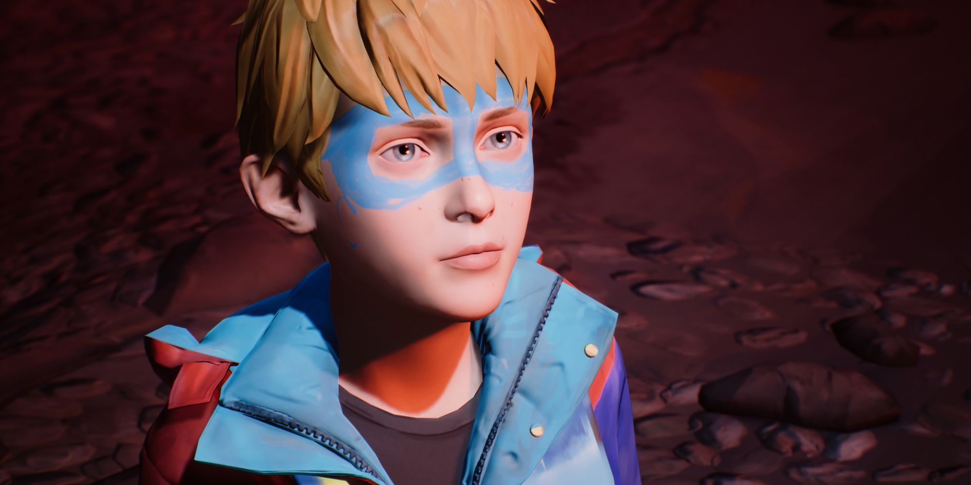 A blonde boy in sky blue and red superhero costume with a blue mask painted over his face.