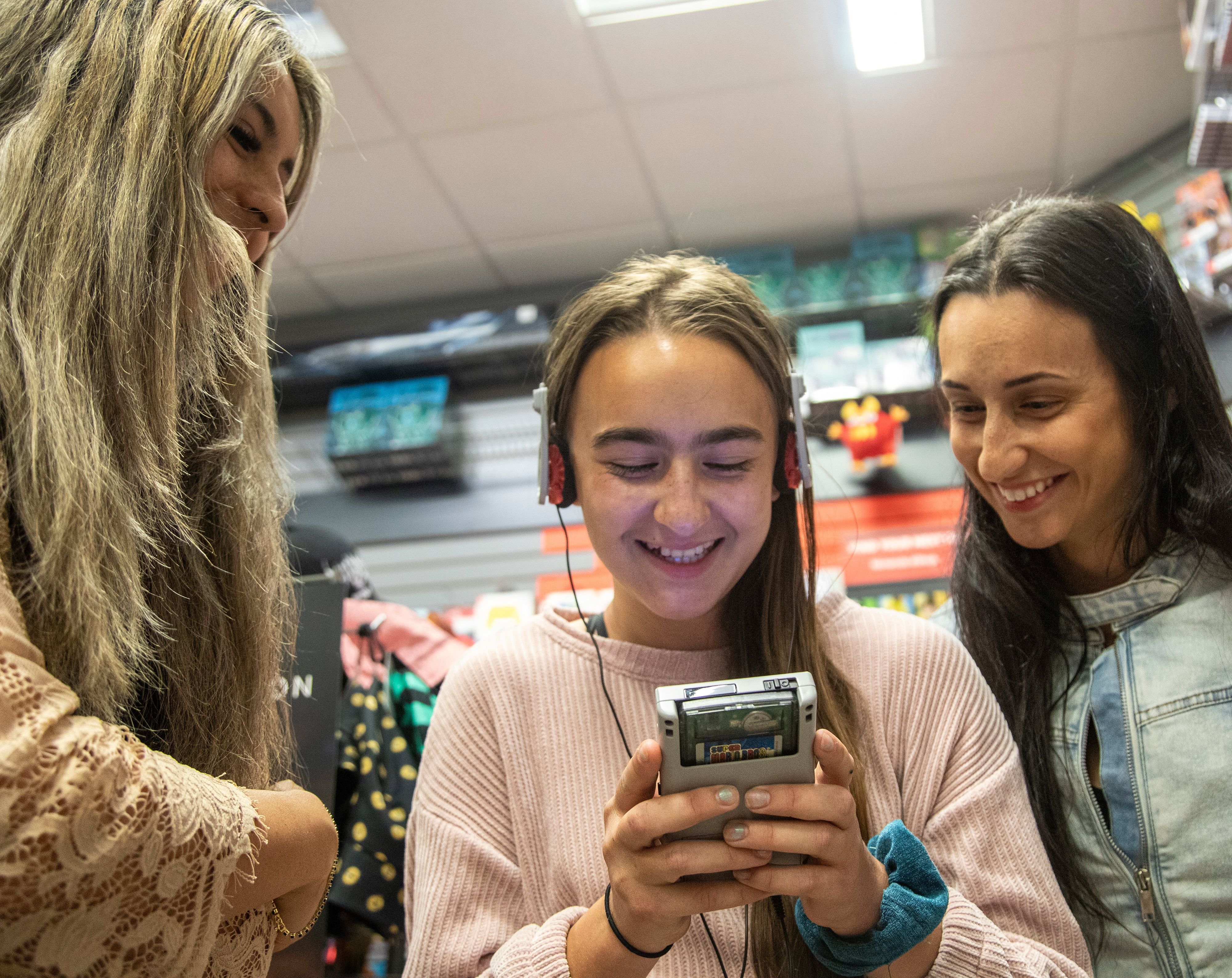 Three women playing a Chromatic handheld.