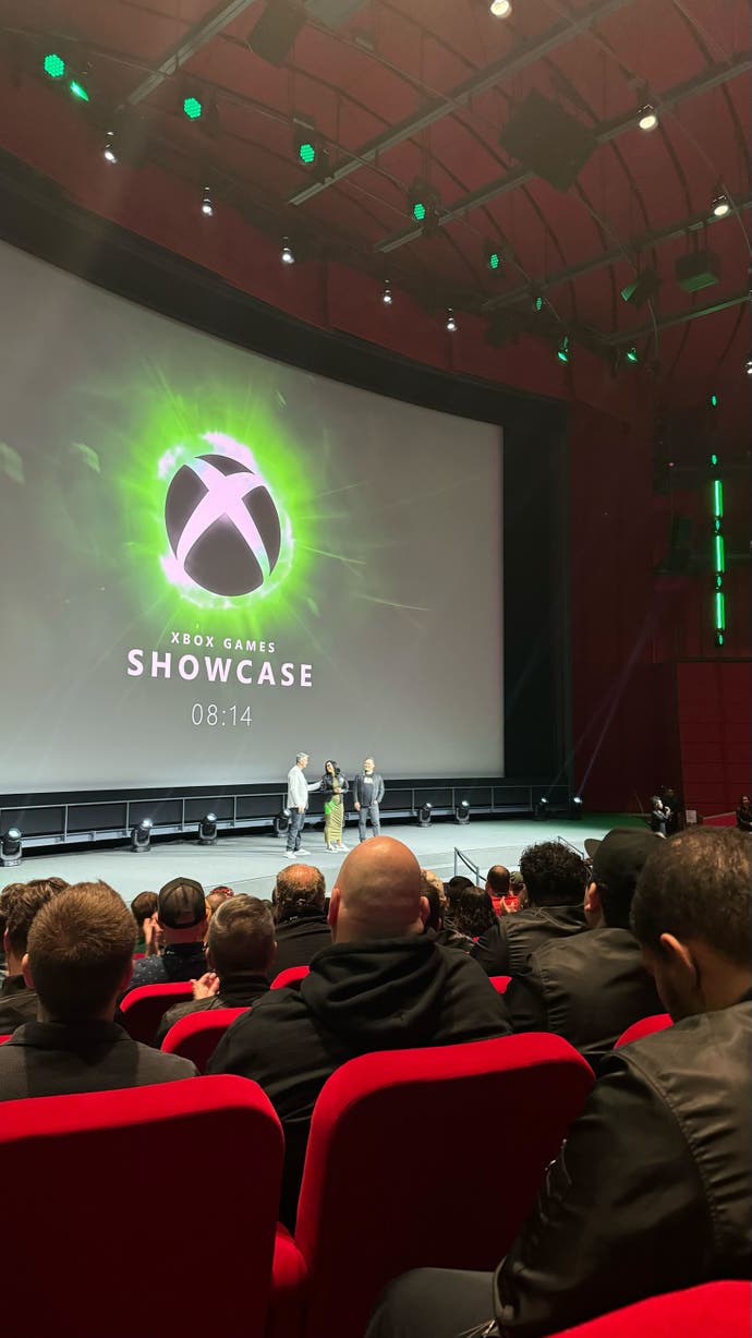 A photo from the Xbox auditorium at Summer Game Fest. We can see people on red chairs and an Xbox logo on the screen.