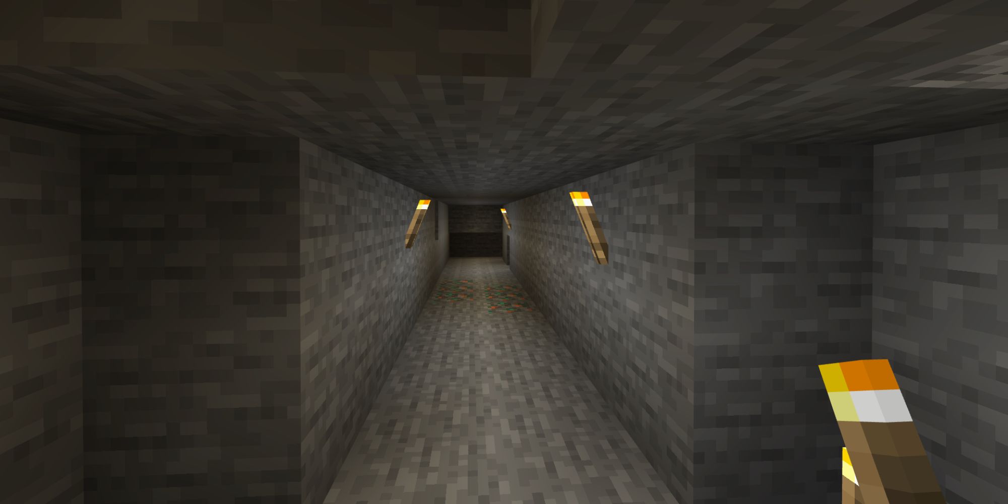 A straight tunnel with torches on the wall.