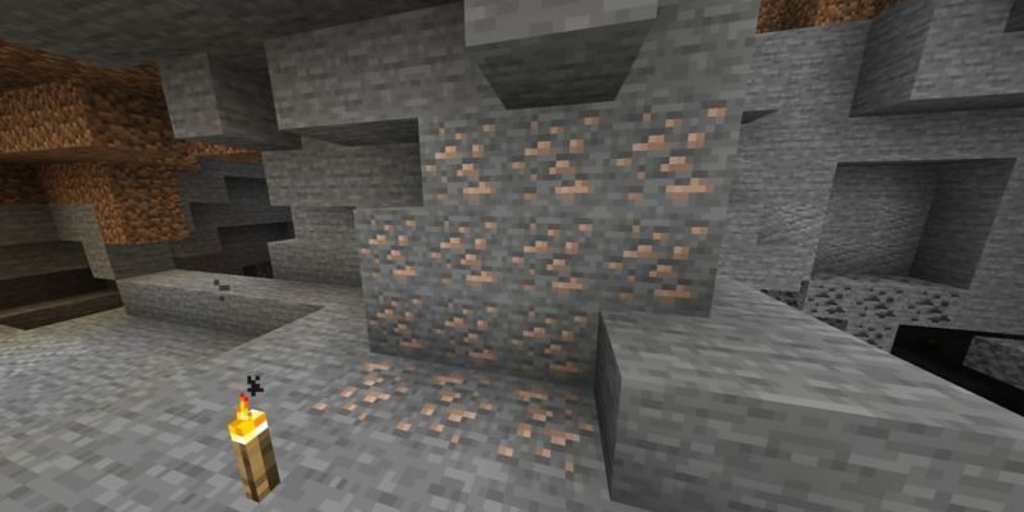 Iron ore in a cave with a torch nearby.