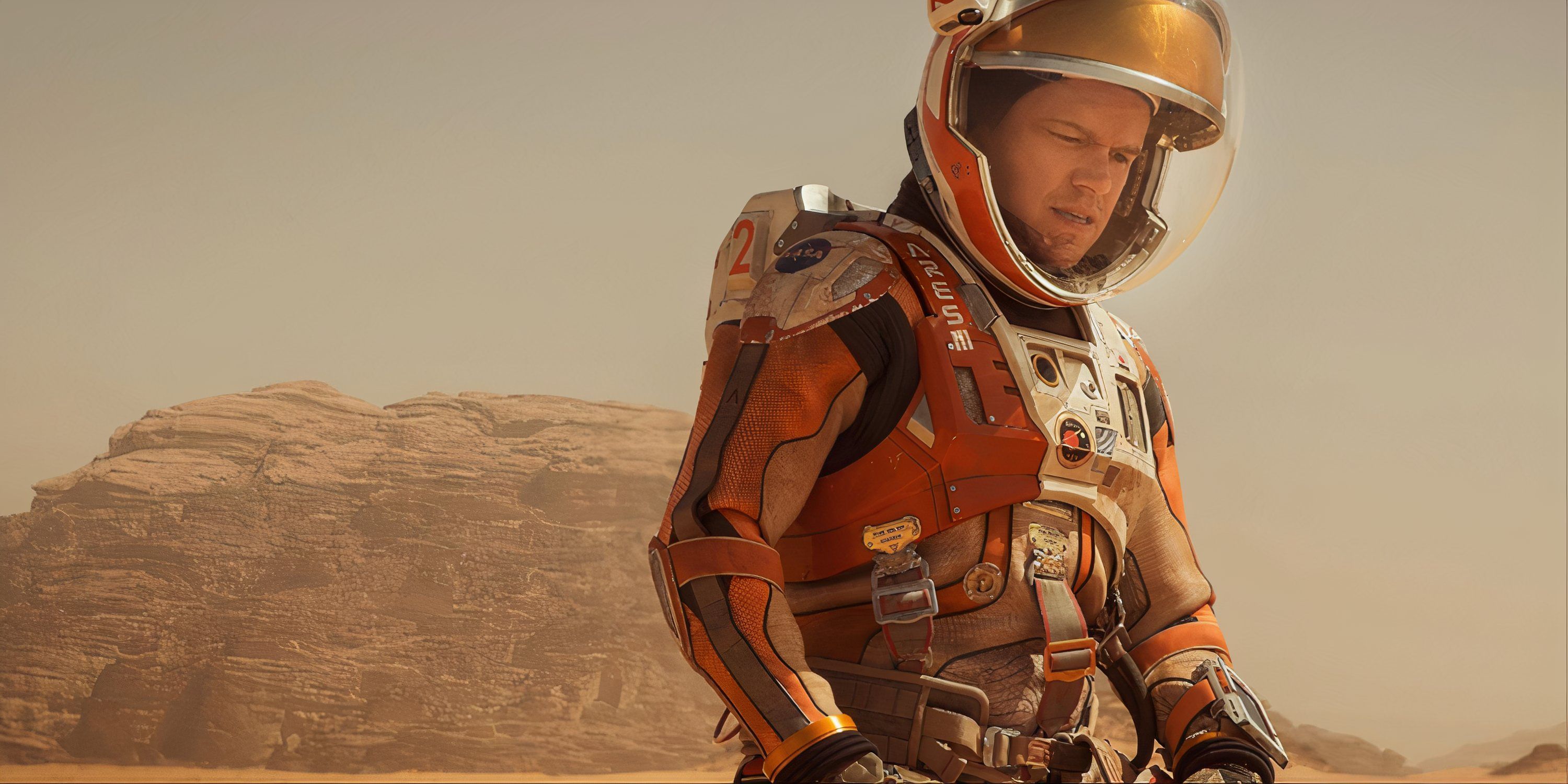 A hopeless Matt Damon on his knees and staring down at the Martian soil in The Martian.