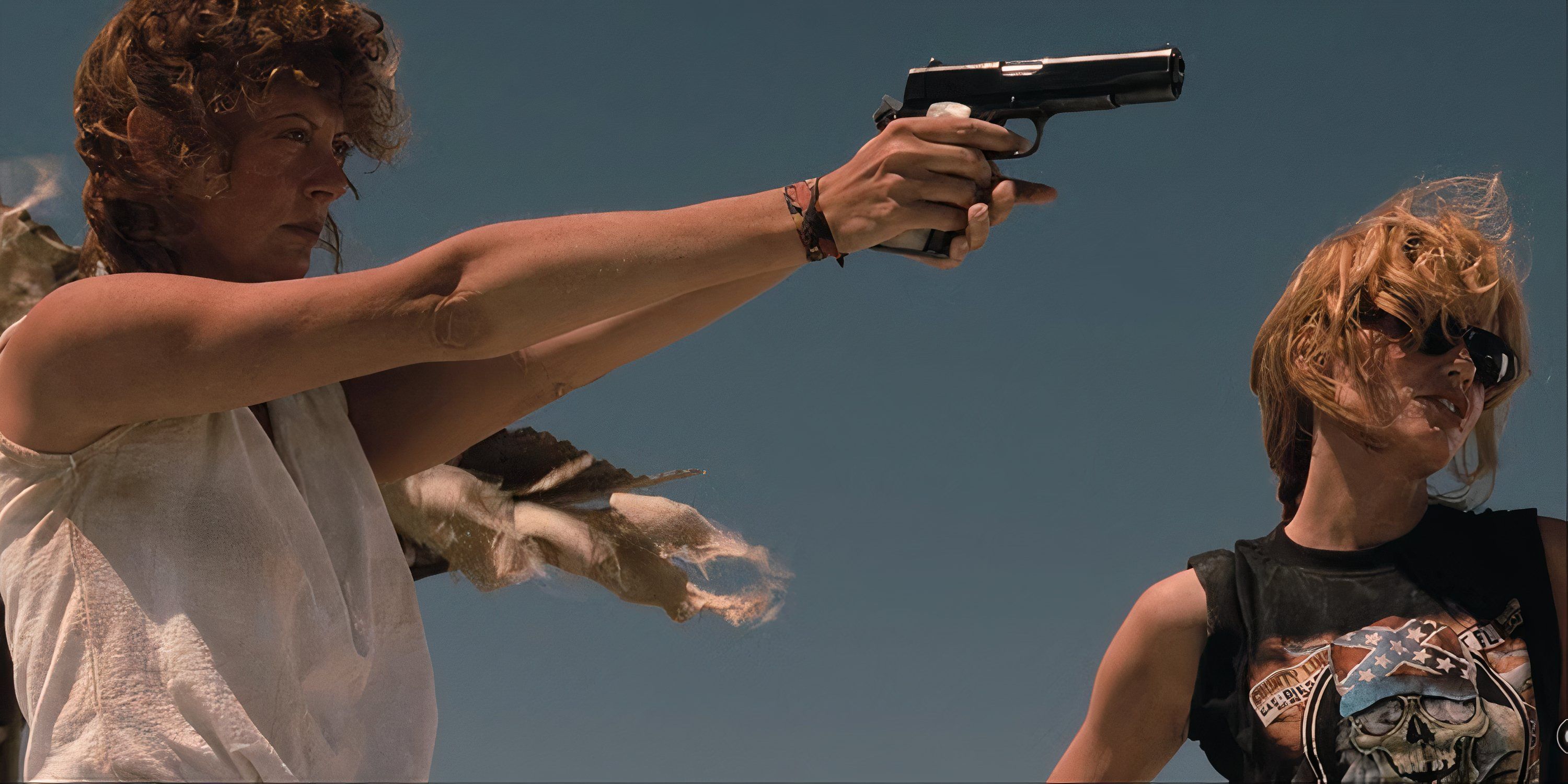 Susan Sarandon aiming a gun as Geena Davis watches by her side in Thelma & Louise.