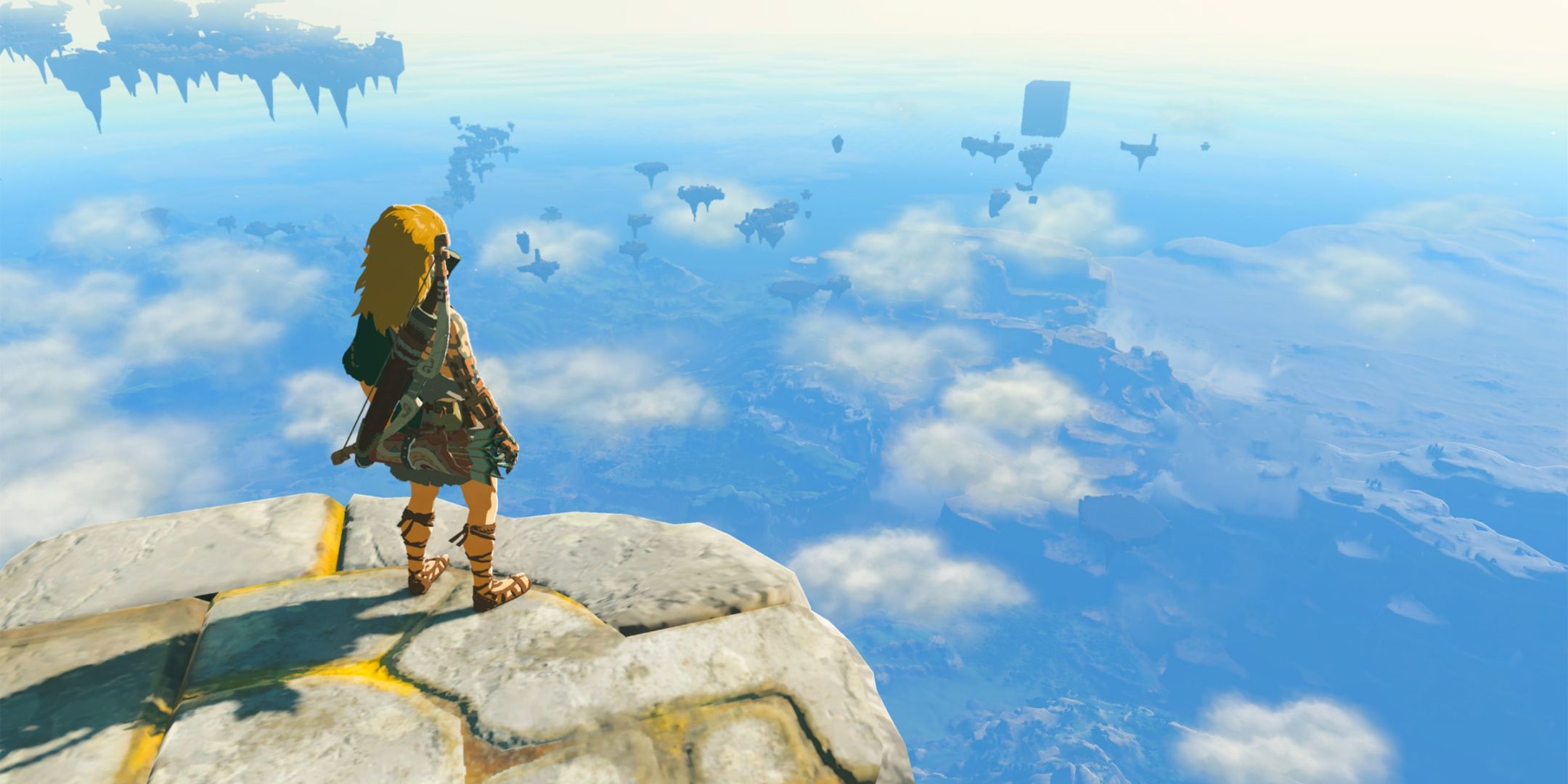 Link standing above the clouds on a tall cliff.