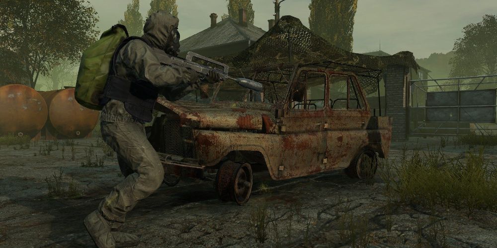 Dayz screenshot of charater in military gear running by rusted out car holding assault rifle.