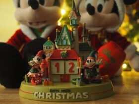 Disney Christmas Countdown Castle in front of a Mickey and Minnie Mouse plush set, with a twinkling tree in the background