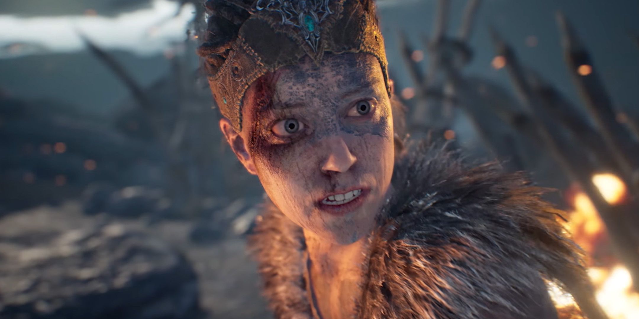 Senua stands in a burning field from Hellblade: Senua's Sacrifice.