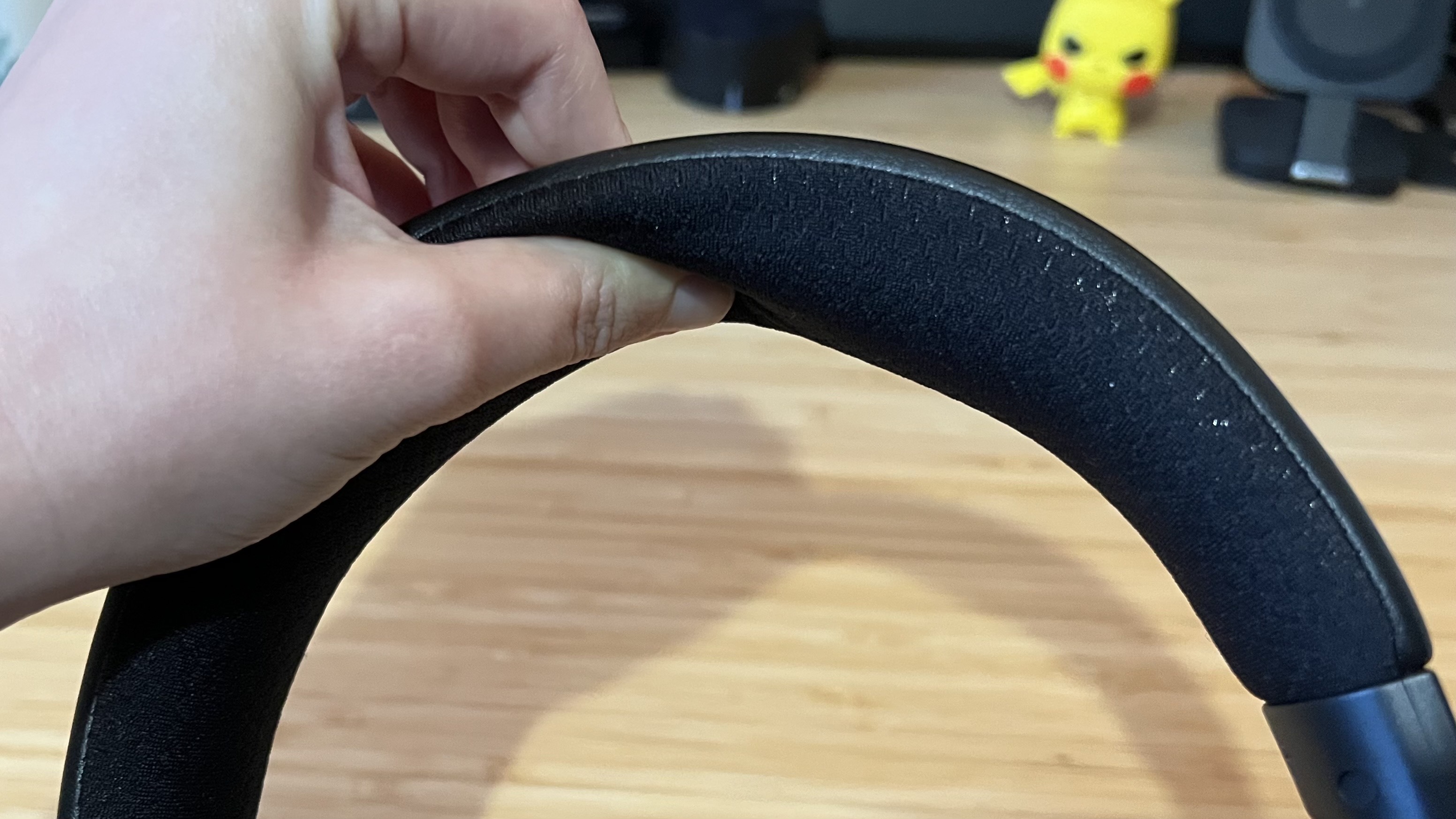 Hand pushing cushioning on headband of Razer Kraken V4 headset