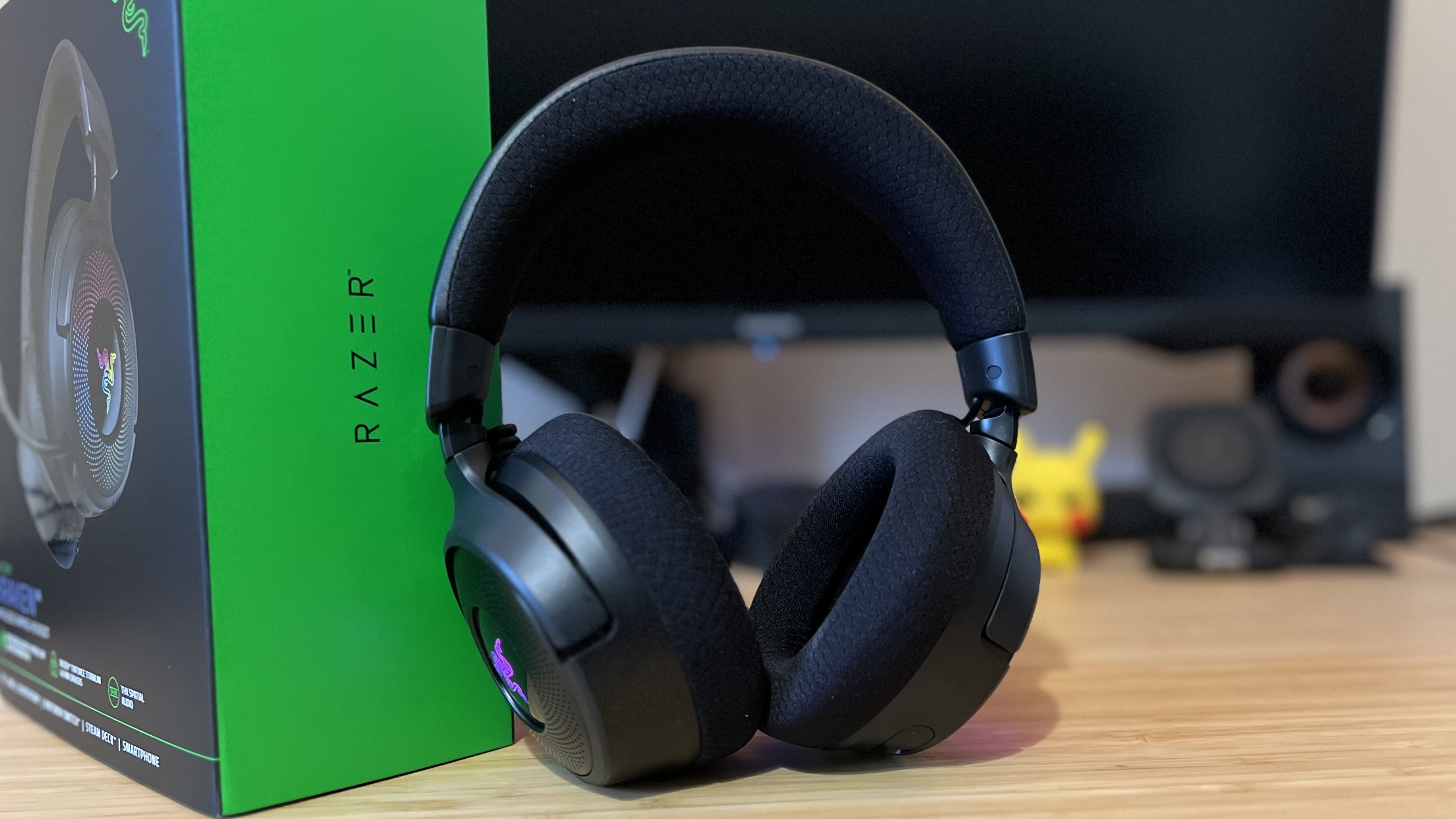 Razer Kraken V4 leaning against box on a wooden desk