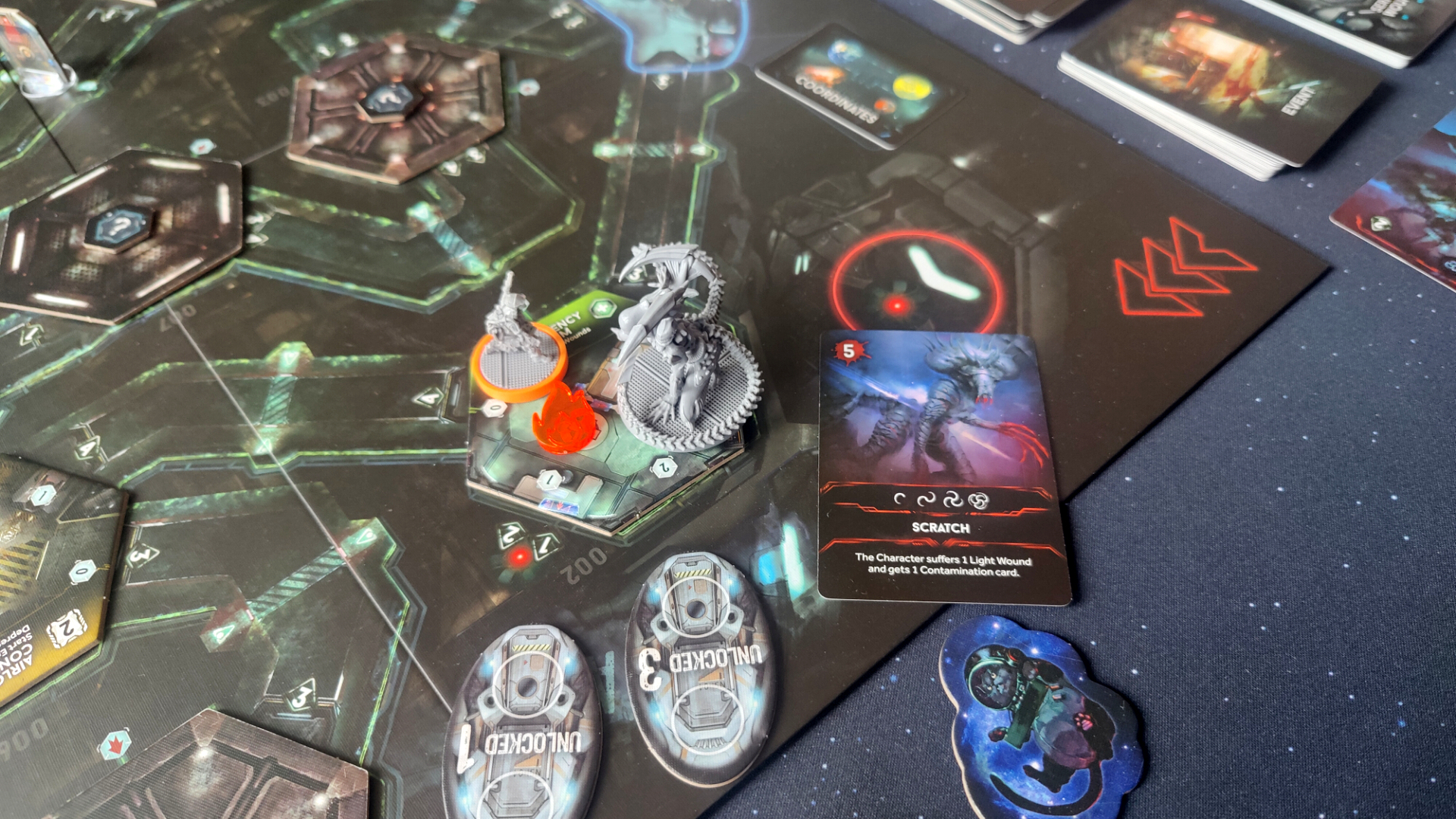 A close-up view of the Nemesis board with character and alien models, tokens, and cards laid out on it