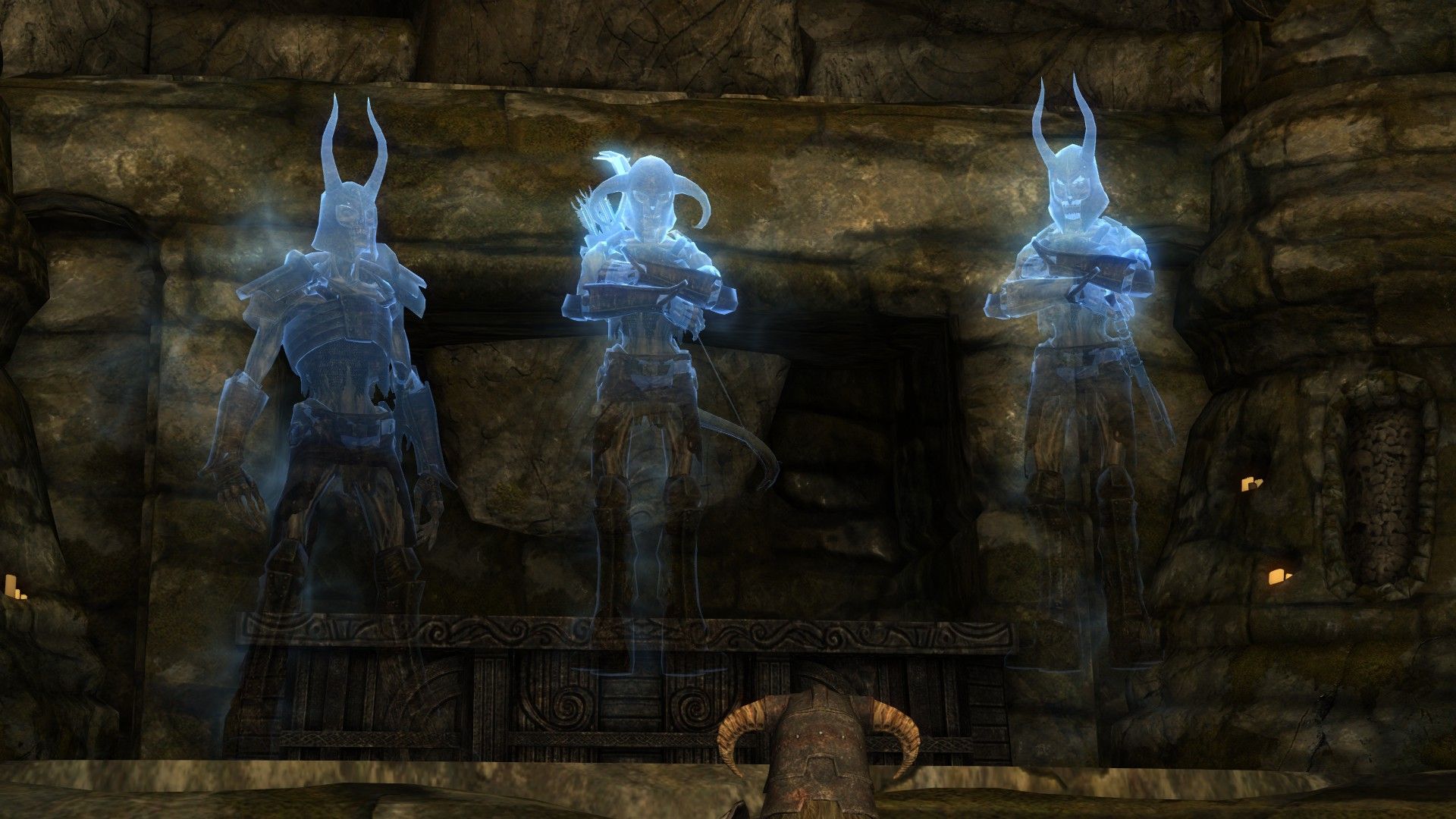 A trio of ghostly brothers look down menacingly at an adventurer inside their tomb in Skyrim.