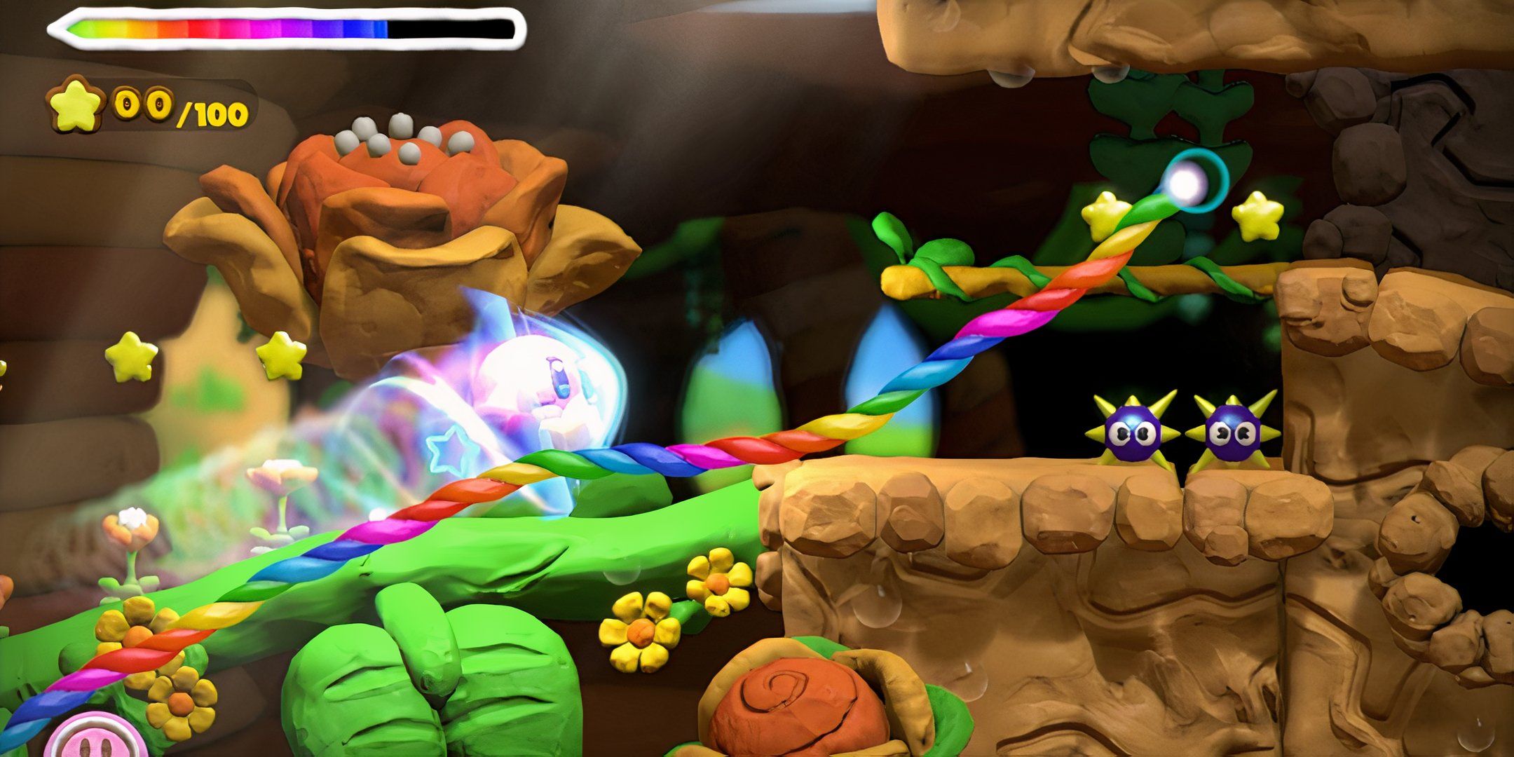 Kirby and the Rainbow Curse screenshot of Kirby on a rainbow trail in front of a beanstalk.