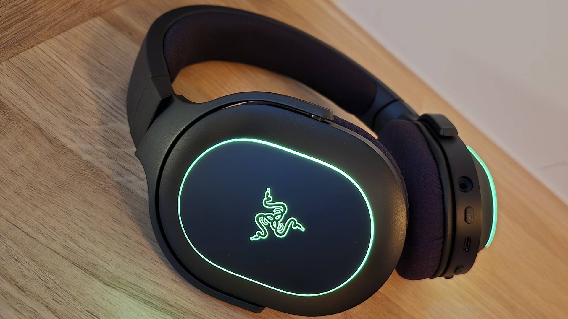 Photo of the Razer Barracuda X Chroma gaming headset on a wooden countertop taken by author Rosalie Newcombe.