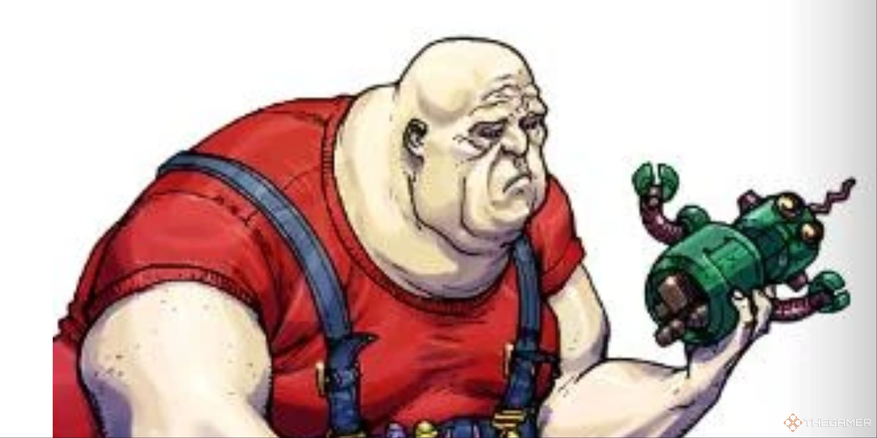 A large, bald man in a red t-shirt and denim overalls looks at a toy robot in his hand with a forlorn expression.