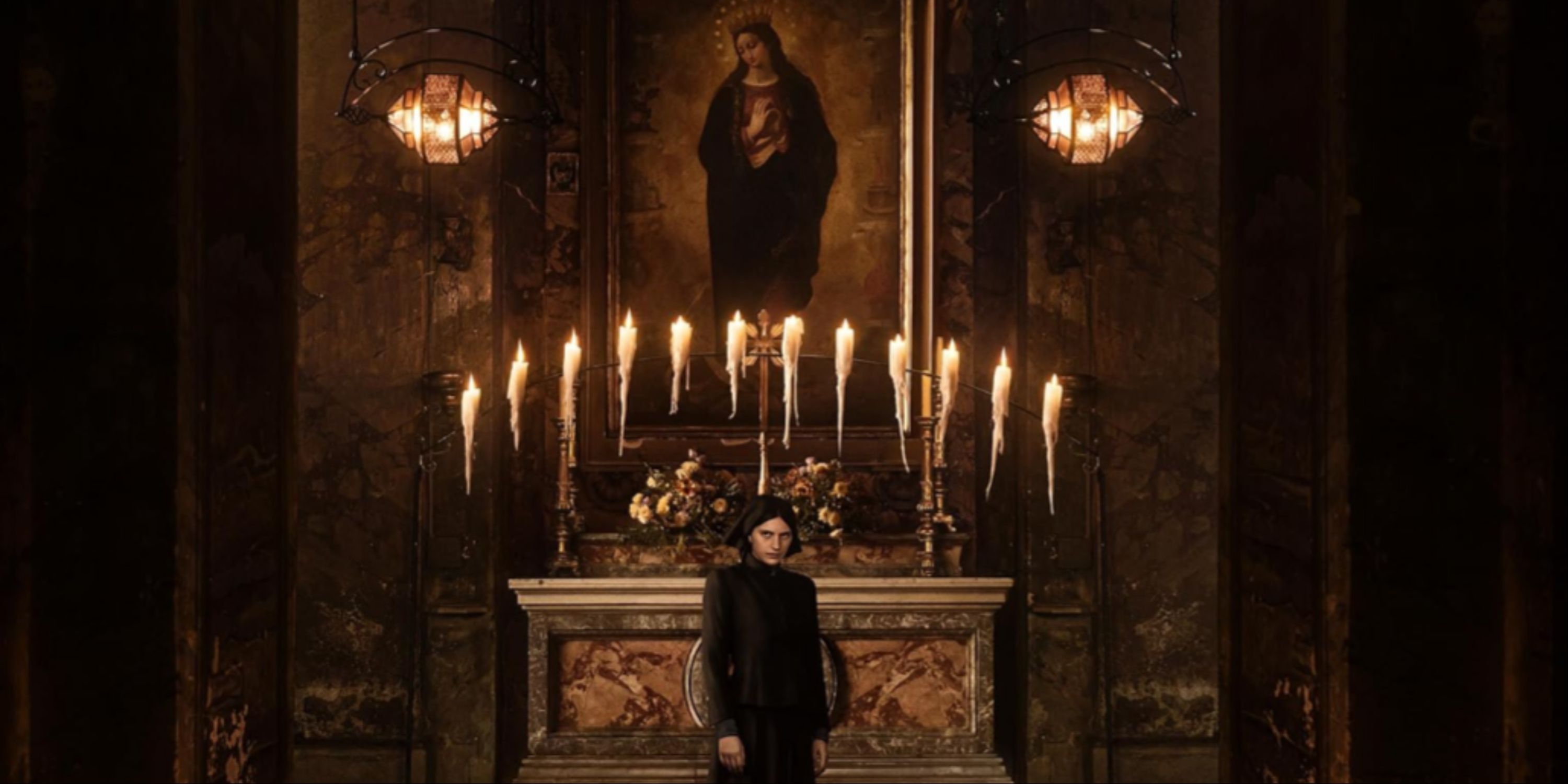 Nell Tiger Free as Margaret facing the camera by an altar with candles surrounding her in The First Omen.