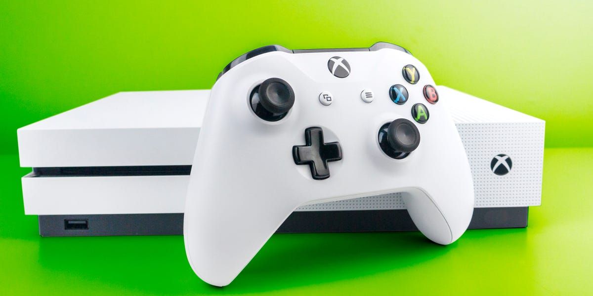 The white Xbox One S console and controller in front of a green background