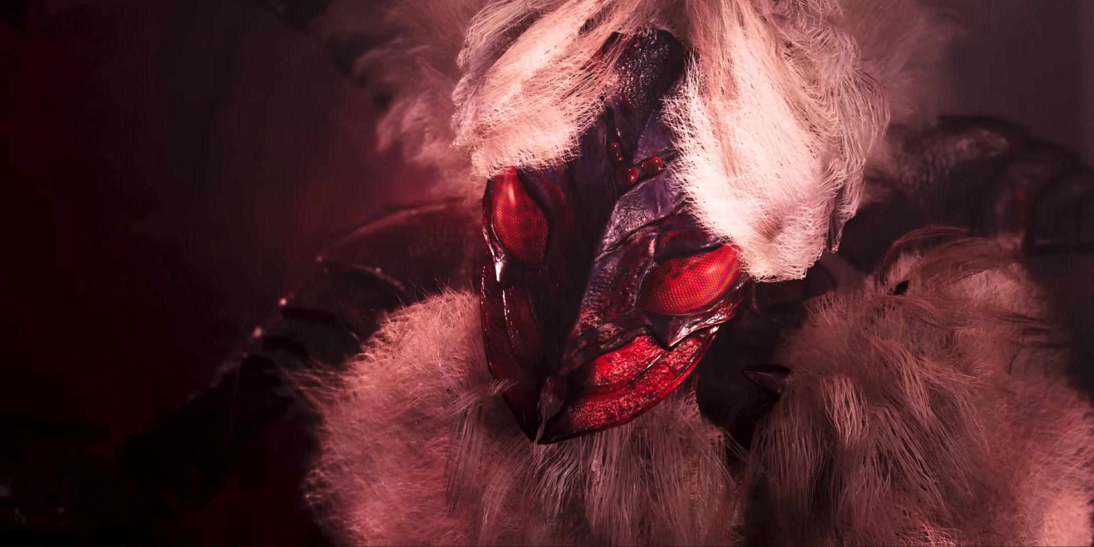 A close up of a large red and white furry spider creature in monster Hunter Wilds