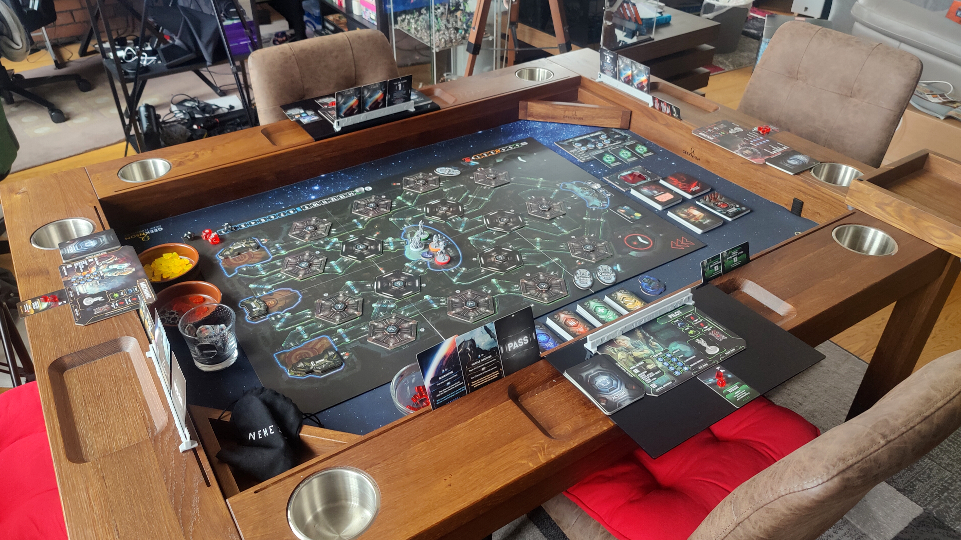 Nemesis board, tokens, and pieces set up in a gaming table, with chairs surrounding it