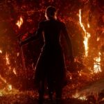 Path of Exile 2 screenshot from the opening cinematic trailer, showing someone stood surrounded by flames.