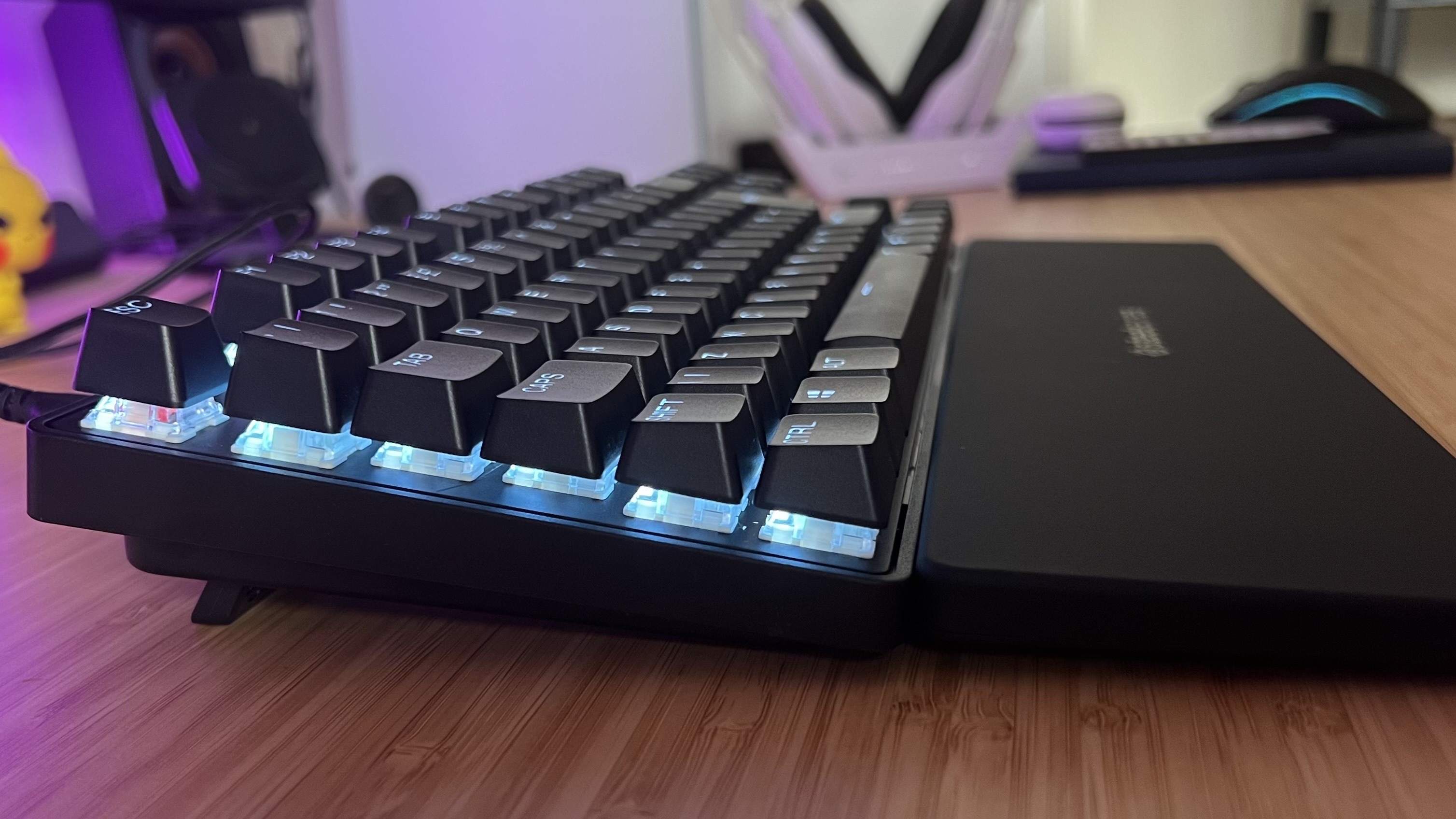 Side of SteelSeries Apex Pro TKL Gen 3 keyboard at full elevation on a wooden desk