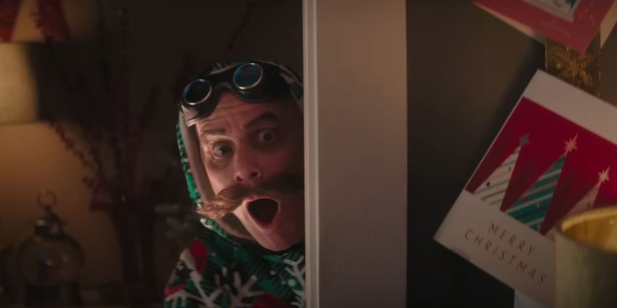 Jim Carrey as Eggman in Sonic 3. He is wearing Christmas pajammas and peaking around the corner with a shocked expression