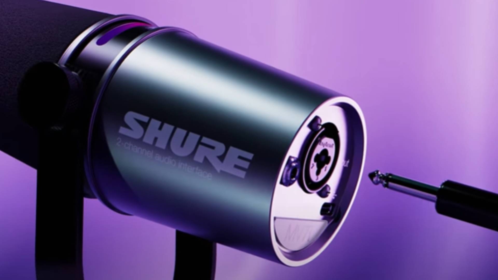 Screenshot from The Shure MV7i YouTube video showing an XLR port on the back of the microphone with a purple background.