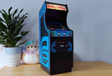 Quartercade Taito Bubble Bobble arcade machine with marquee illuminated sitting on woodgrain surface