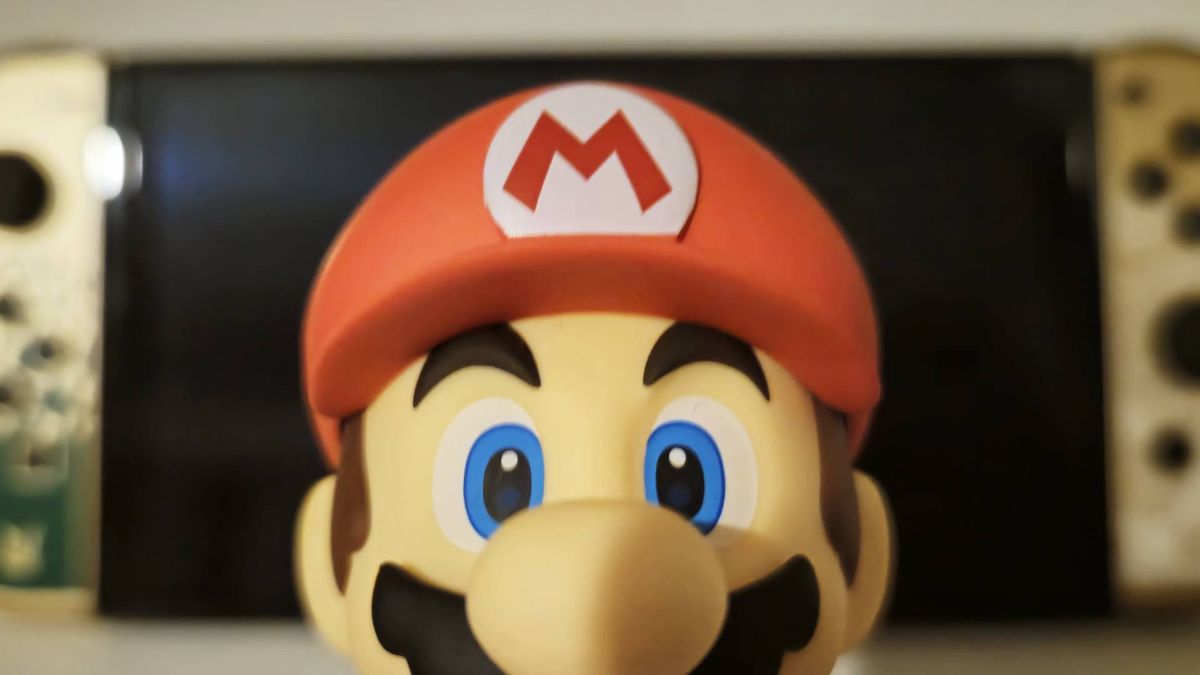 Image taken by author Rosalie Newcombe of the official Super Mario Good Smile Company Nendoroid figure sitting infront of a Nintendo Switch OLED.