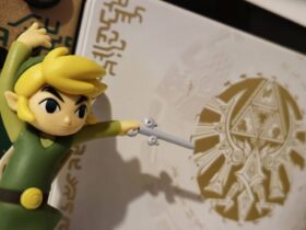 Image of the Wind Waker Link amiibo standing in front of the Tears of the Kingdom Nintendo Switch OLED.