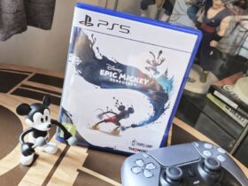 Image of the PS5 copy of Epic Mickey Rebrushed sitting on a coffee table with a Mickey toy and DualSense controller sitting infront of it.