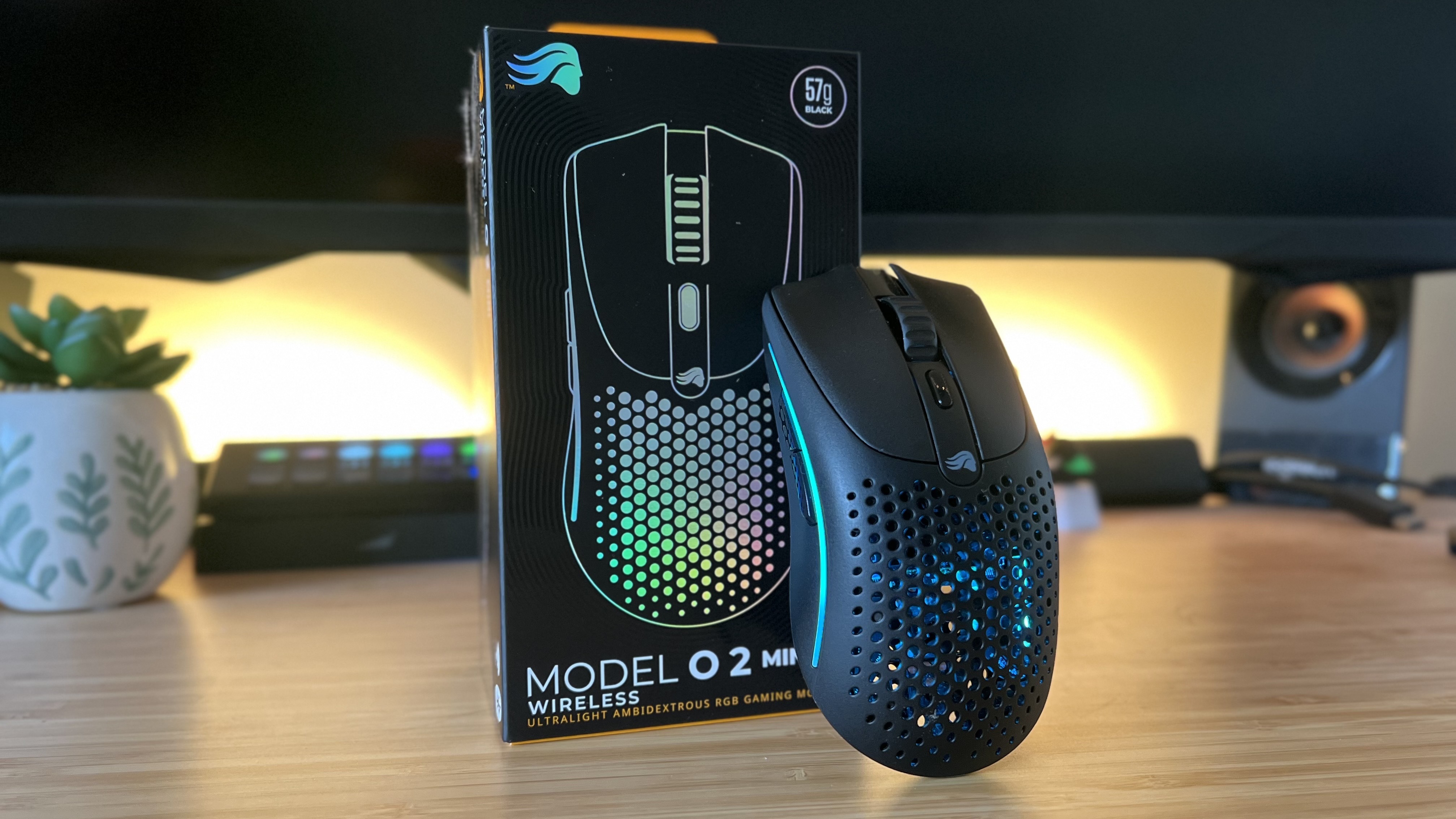 Glorious Model O 2 Mini Wireless gaming mouse leaning against its packaging on a wooden gaming desk