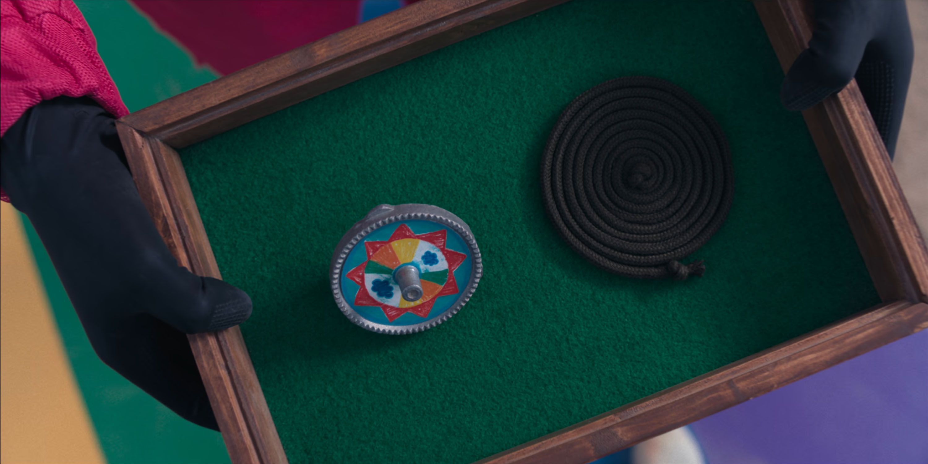 A Paengi Chigi spinning top and a coil of twine presented inside a green felt box in Squid Game.