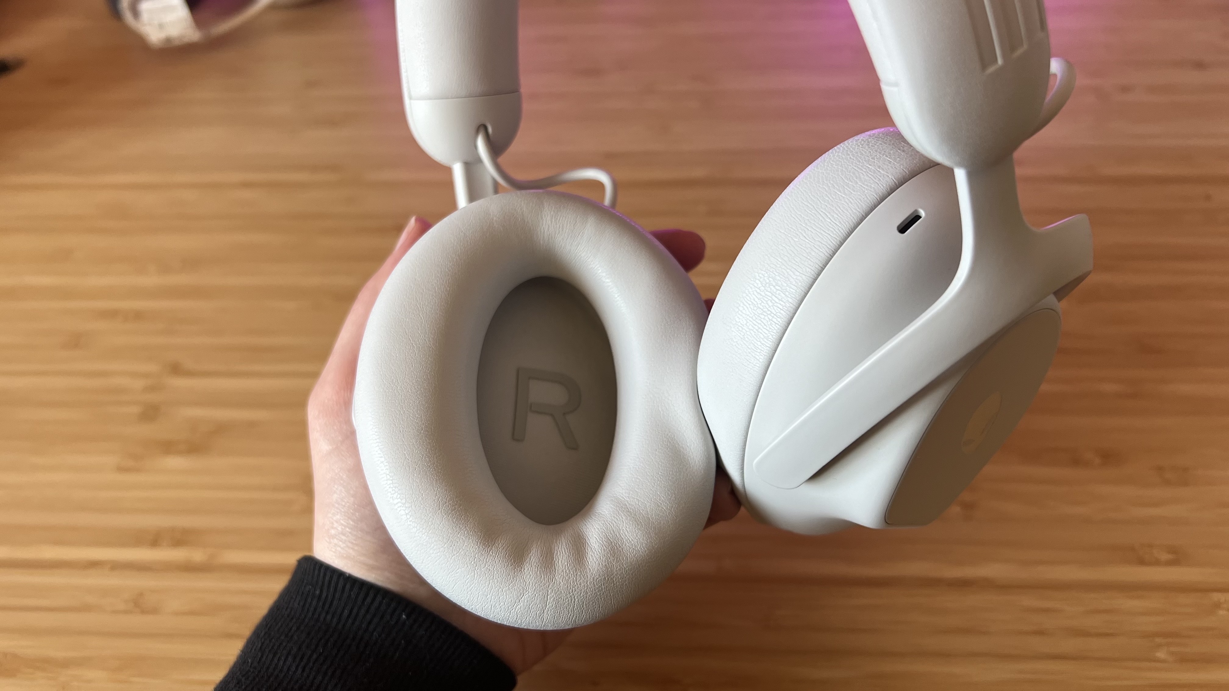 Close up on Alienware Pro Wireless right earcup being held by a reviewer against a wooden desk